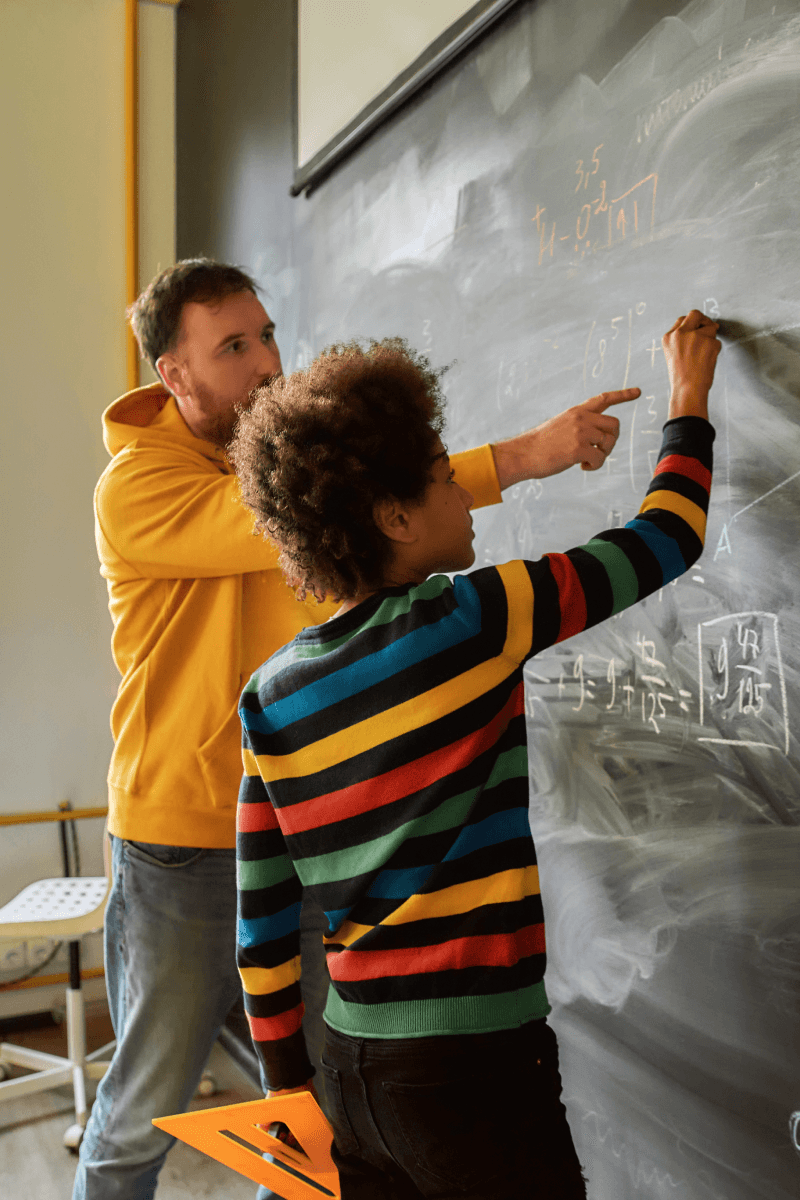 Lehrer und Schüler stehen an Tafel